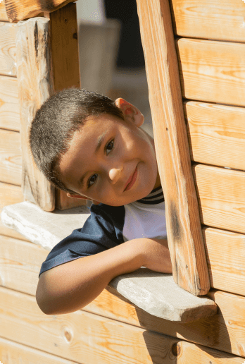 Niño mirando por una ventana de madera